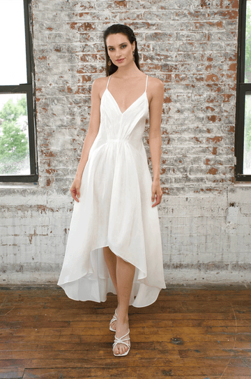 luxurious white hemp silk dress with thin shoulder straps, waist gather, flared hem that is short in front and long in back, worn with white sandals